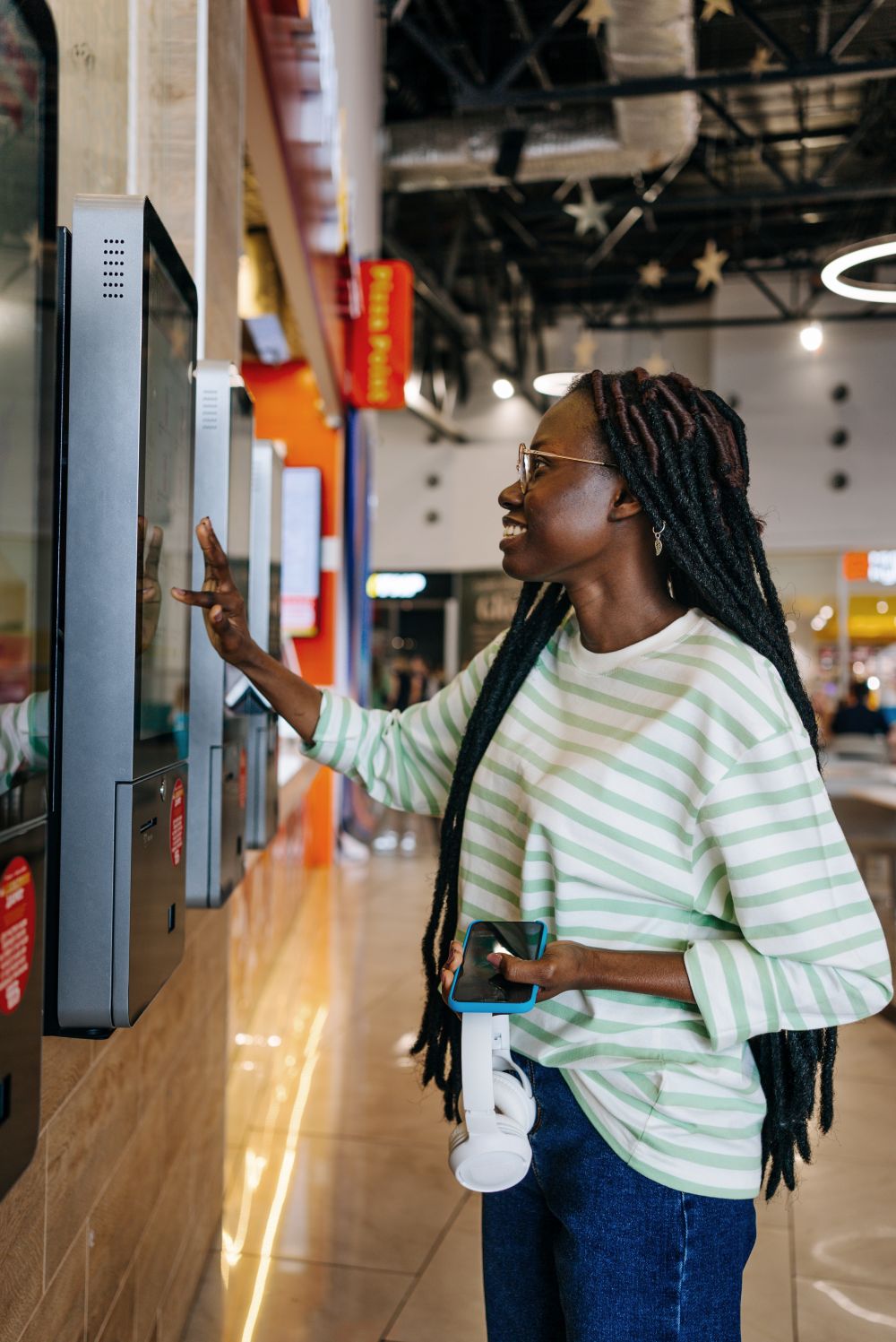 African American girl Using Self-Service Kiosk at Fast Food Restaurant.