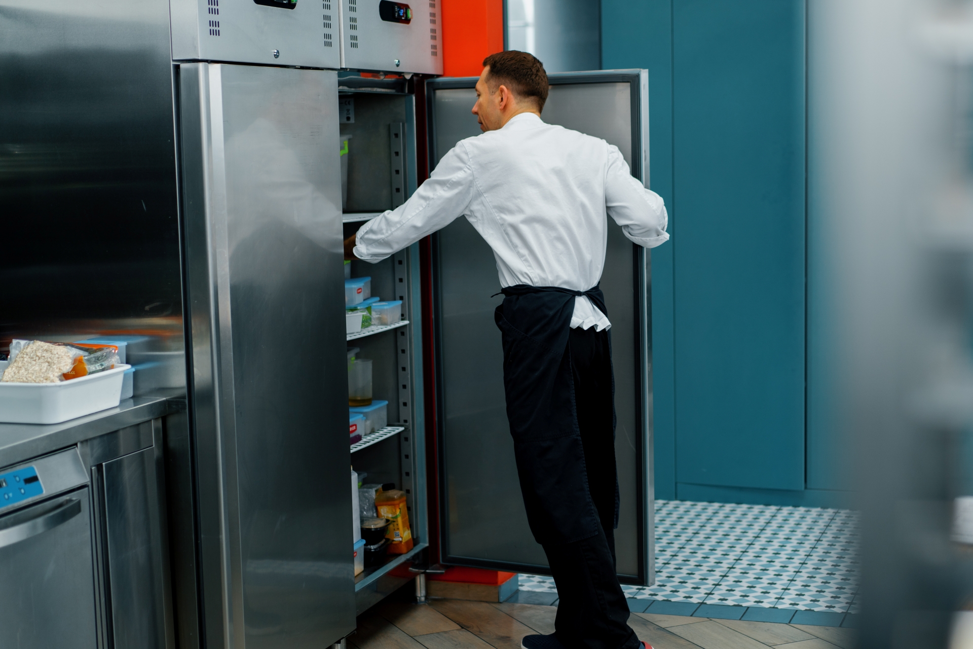 professional kitchen chef looks into the fridge and chooses ingredients for cooking food concept